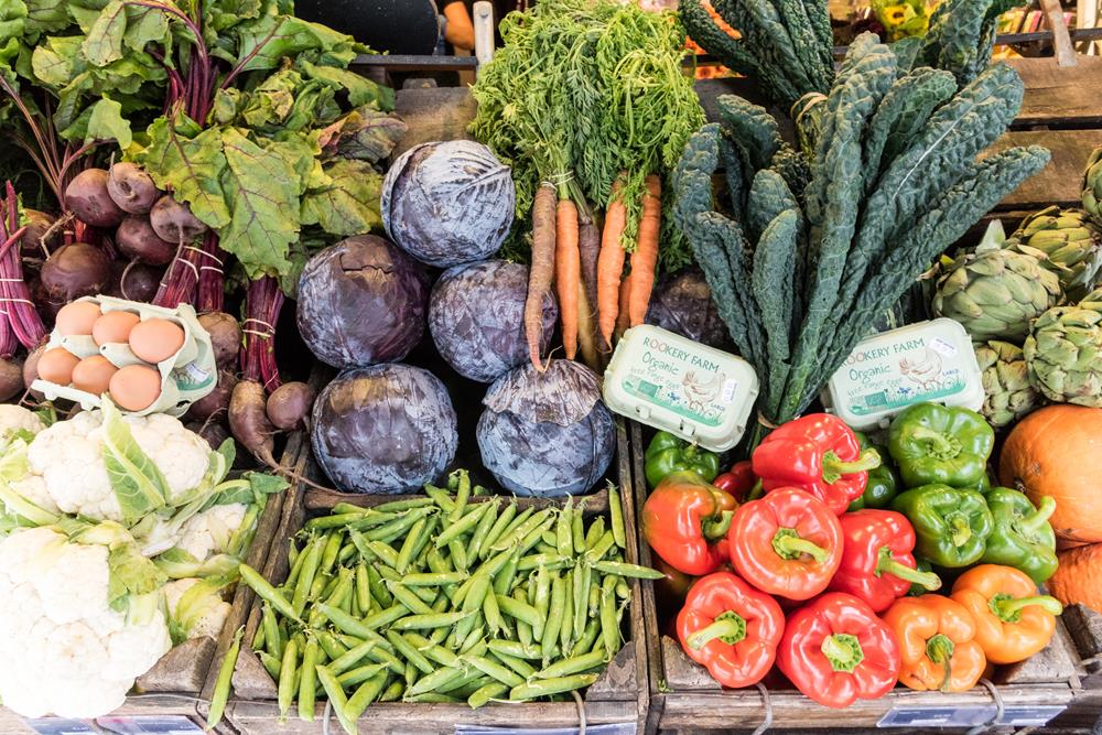 Boxes of Rookery Farm eggs nestled among vegetables in a greengrocer's shop.